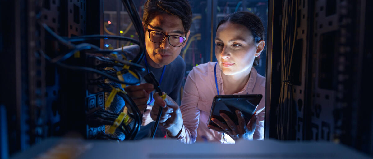 Diverse Ingenieure mit digitalem Tablet inspizieren den Server im Computer-Serverraum. Datenbankserver-Management- und Wartungskonzept. © Wavebreakmedia/ Getty Images