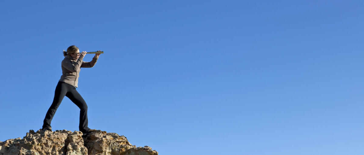 Frau auf Bergspitze mit Fernrohr © DOUGBERRY / Getty Images