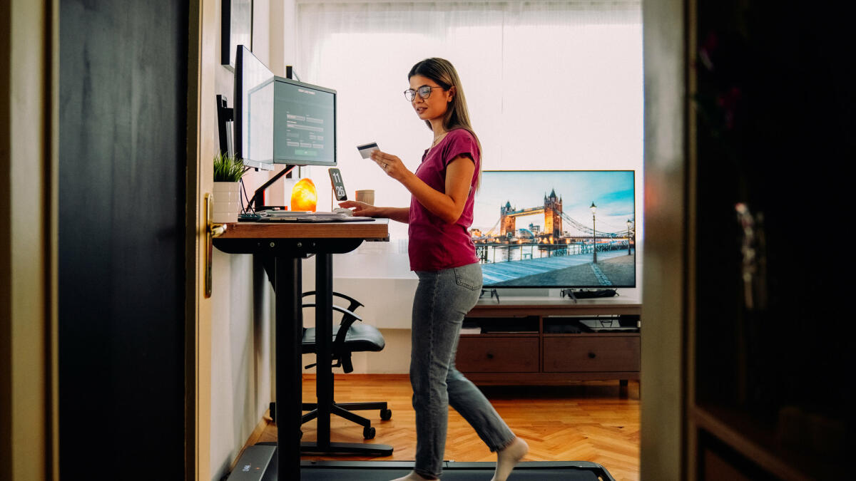 Frau arbeitet auf Laufband an einem Stehschreibtisch © martin-dm / Getty Images