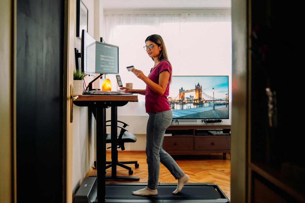 Frau arbeitet auf Laufband an einem Stehschreibtisch © martin-dm / Getty Images