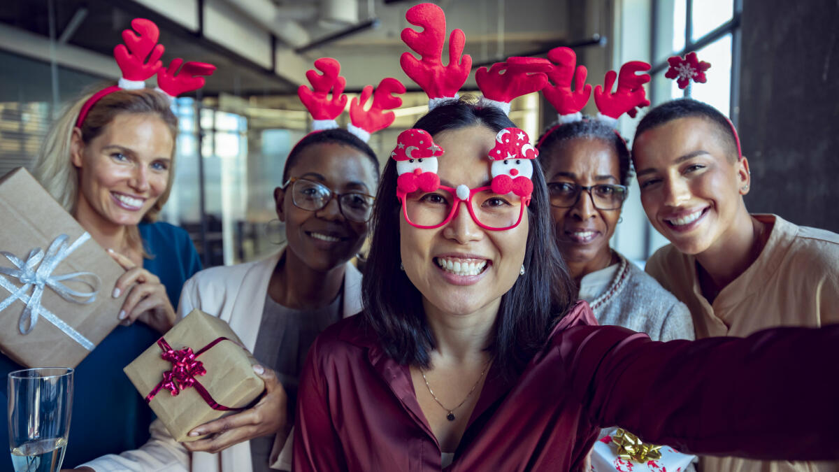 Kollegen mit Weihnachtsbrillen machen Selfie © Marko Geber / Getty Images