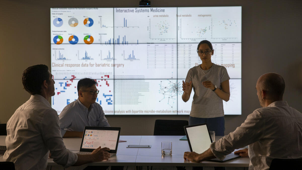 Treffen vor einem großen Informationsgerät zum universellen Nachweis von Genen in einer bestimmten biologischen Probe. © SolStock/ Getty Images