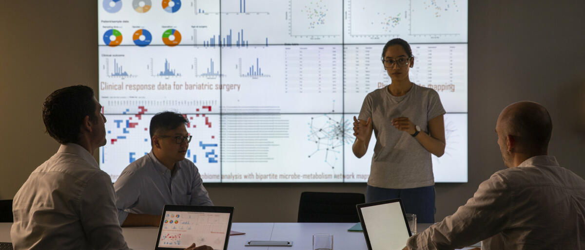 Treffen vor einem großen Informationsgerät zum universellen Nachweis von Genen in einer bestimmten biologischen Probe. © SolStock/ Getty Images