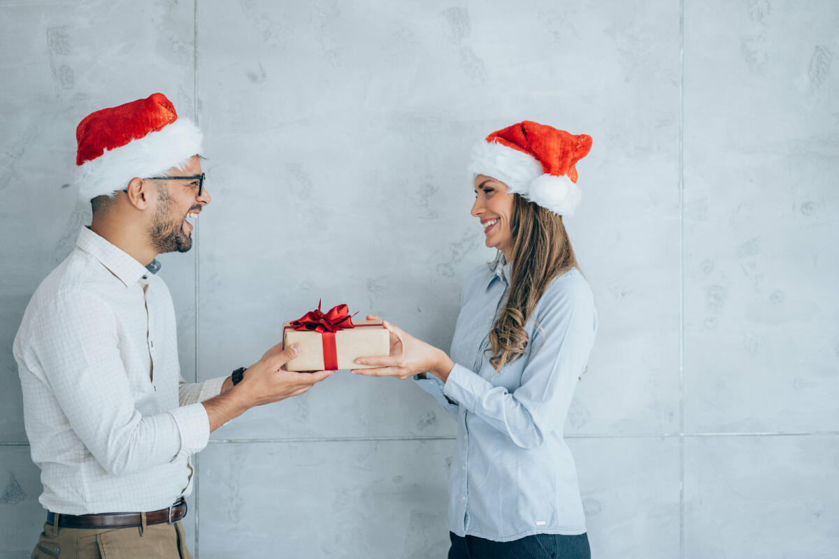 Geschäftsmann schenkt seiner Kollegin ein Geschenk. © VioletaStoimenova / Getty Images