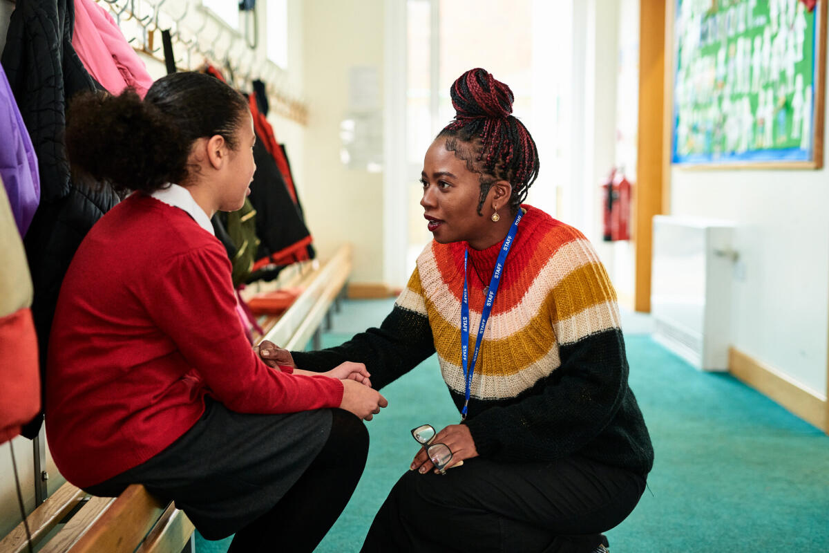 Grundschulmädchen sitzt auf einer Bank und spricht mit einem Lehrer, Probleme, Betreuung, Unterstützung. © 10'000 Hours/ Getty Images