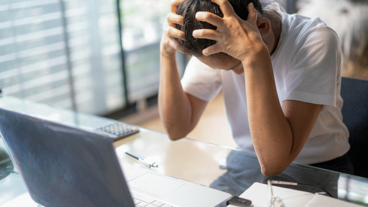 Frau mit Kopfschmerzen sitzt am Laptop © boonchai wedmakawand / Getty Images