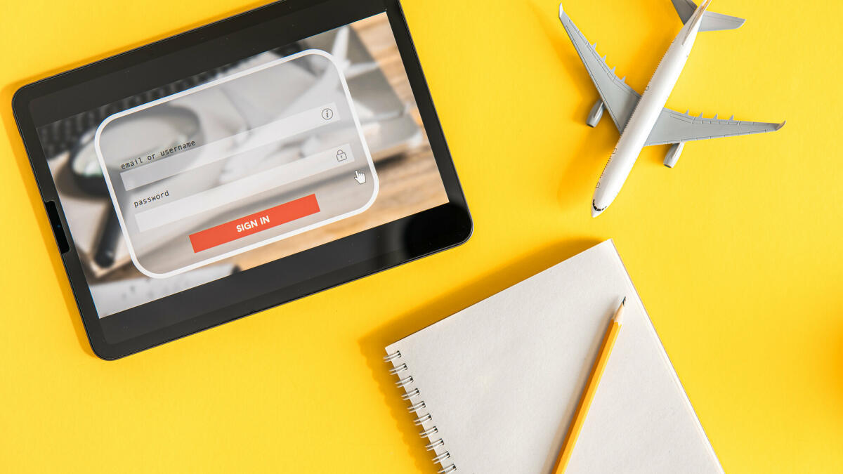 Login-Box, Eingabe von Benutzername und Passwort auf virtueller Digitalanzeige, Notebook und Flugzeug auf gelbem Hintergrund © puhimec / Getty Images
