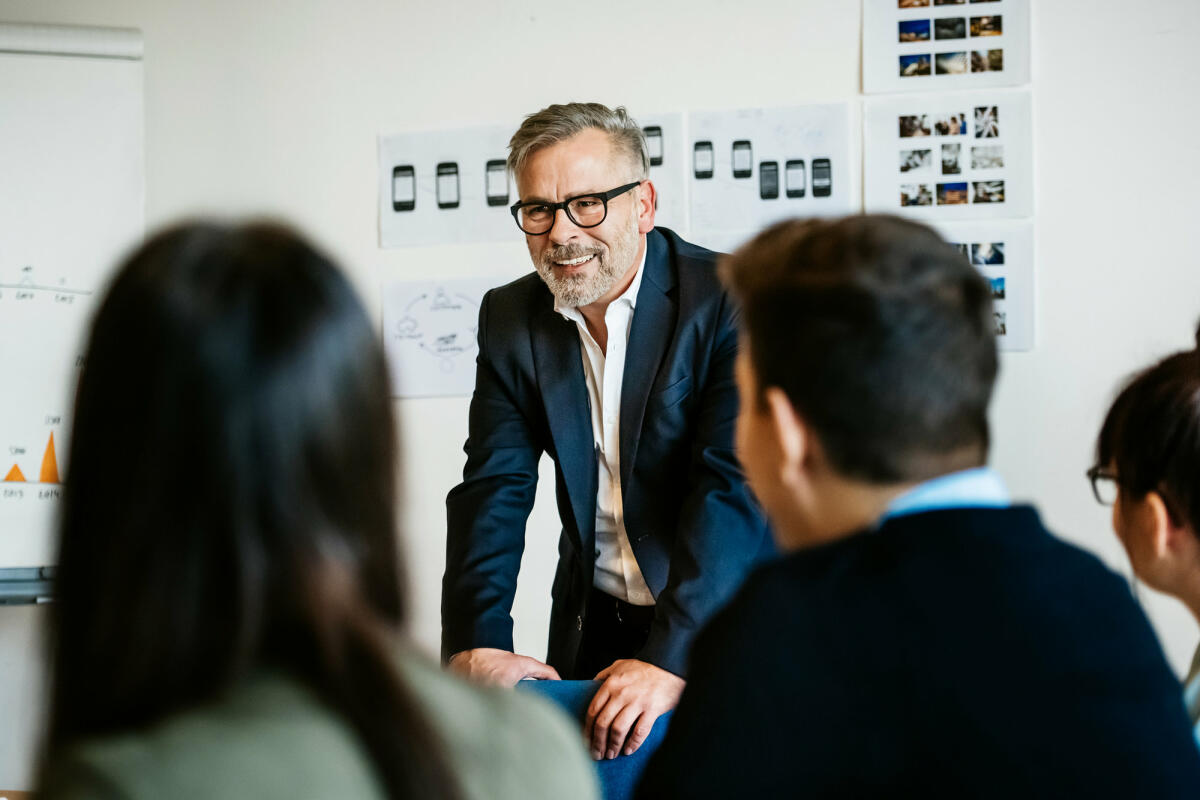 Lachender Mann im Anzug steht vor Mitarbeitern © Tom Werner / Getty Images