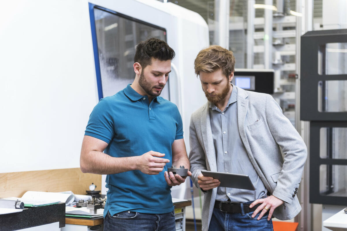 Zwei Männer stehen mit Tablet in einer modernen Fabrik © Westend61 / Getty Images