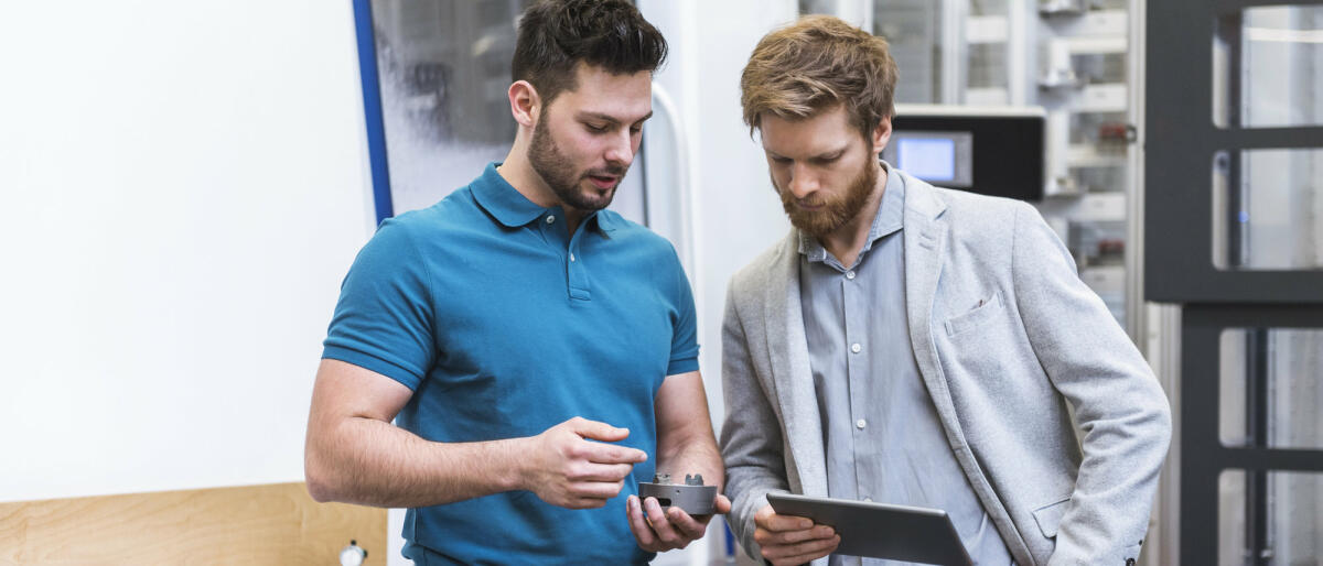 Zwei Männer stehen mit Tablet in einer modernen Fabrik © Westend61 / Getty Images