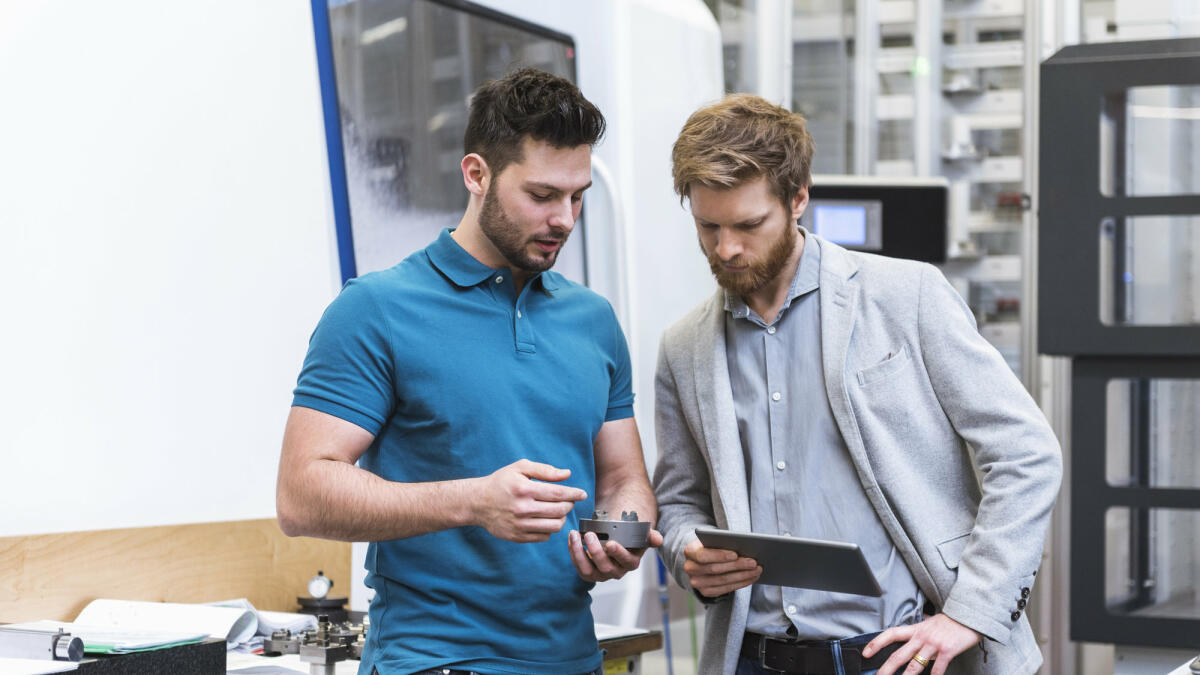 Zwei Männer stehen mit Tablet in einer modernen Fabrik © Westend61 / Getty Images