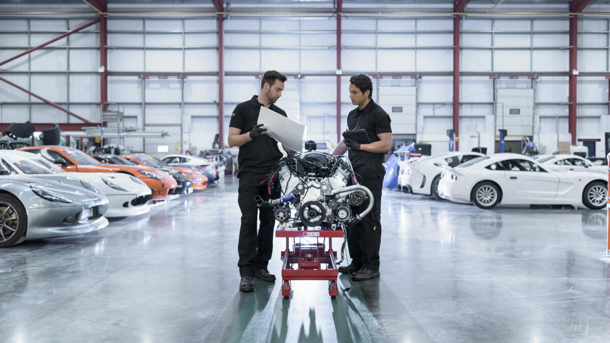 Zwei junge Automobilingenieure stehen vor einem Automotor und beraten sich. © Monty Rakusen / Getty Images