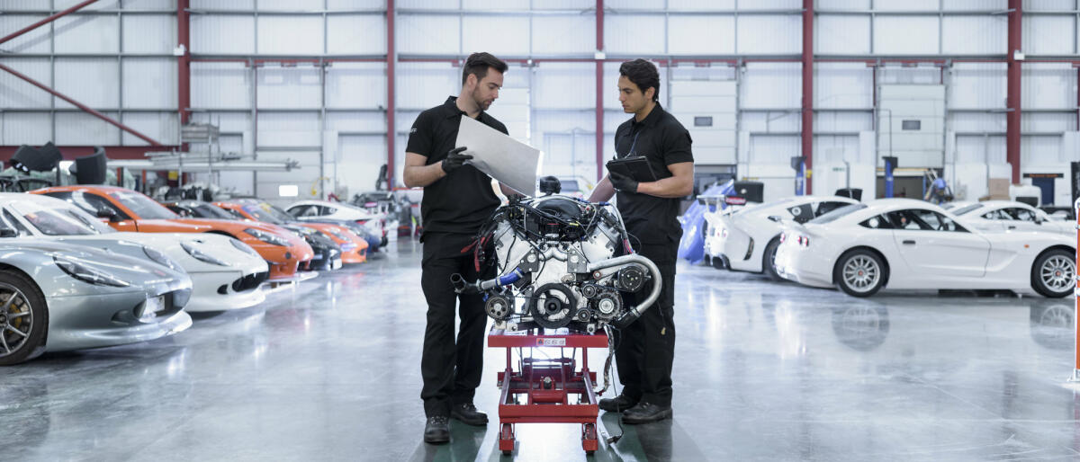 Zwei junge Automobilingenieure stehen vor einem Automotor und beraten sich. © Monty Rakusen / Getty Images