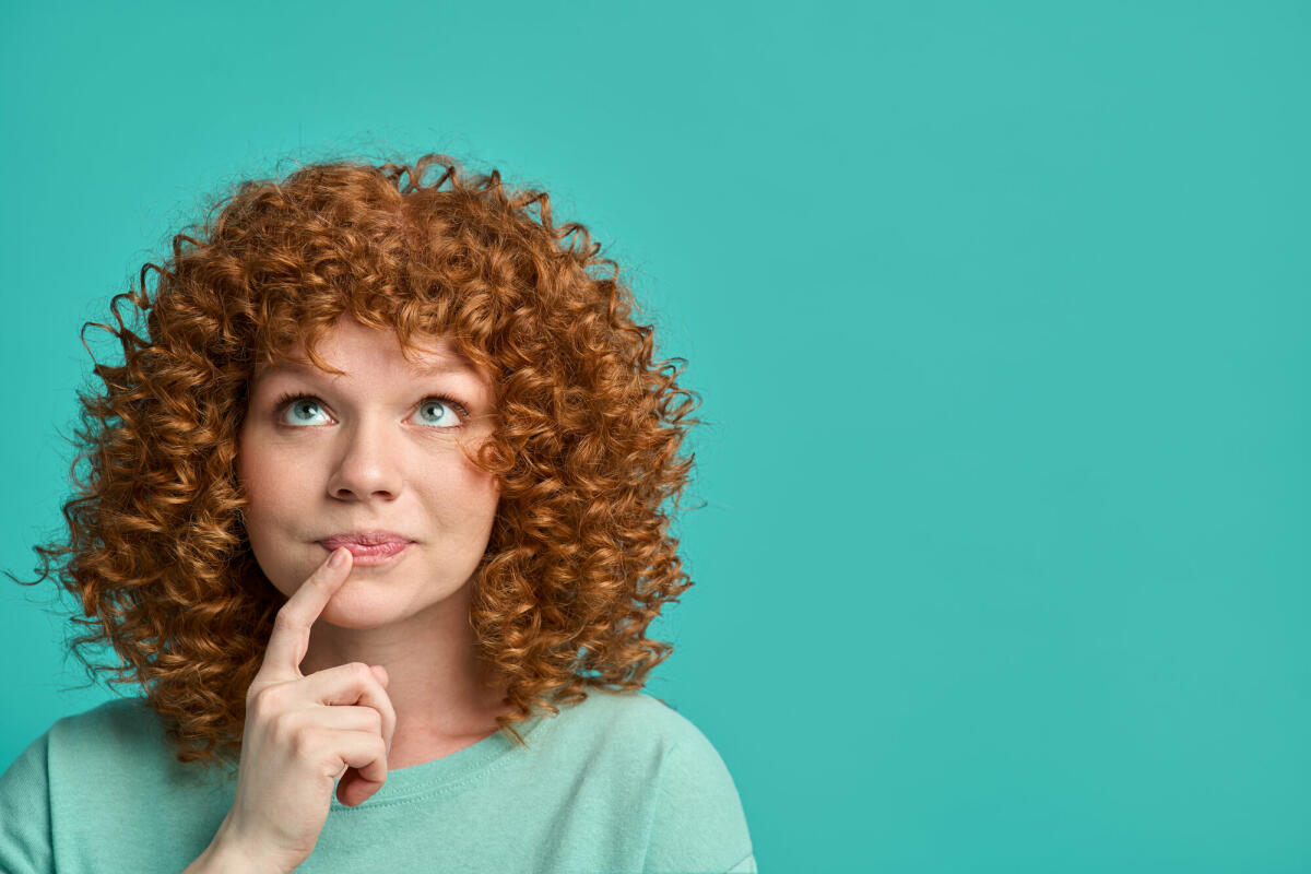 Junge rothaarige Frau Hipster Teenager mit lockigem Haar tragen lässige Kleidung über türkisfarbenen Hintergrund © Yaroslav Olieinikov / Getty Images