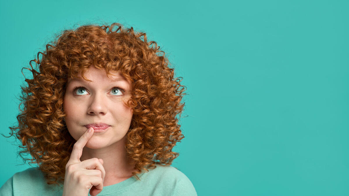 Junge rothaarige Frau Hipster Teenager mit lockigem Haar tragen lässige Kleidung über türkisfarbenen Hintergrund © Yaroslav Olieinikov / Getty Images