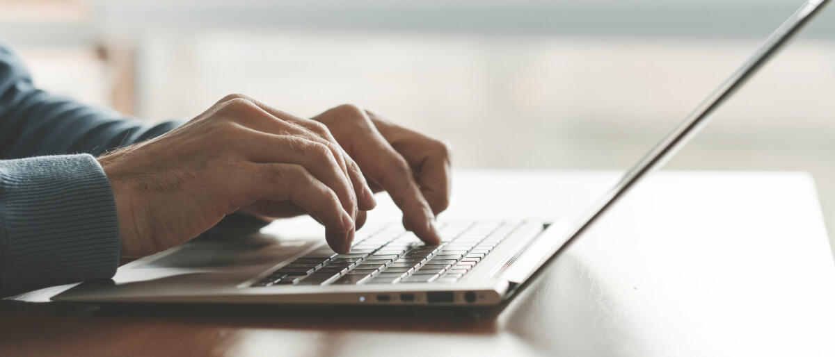 Hände tippen auf Laptop © Igor_kell / Getty Images