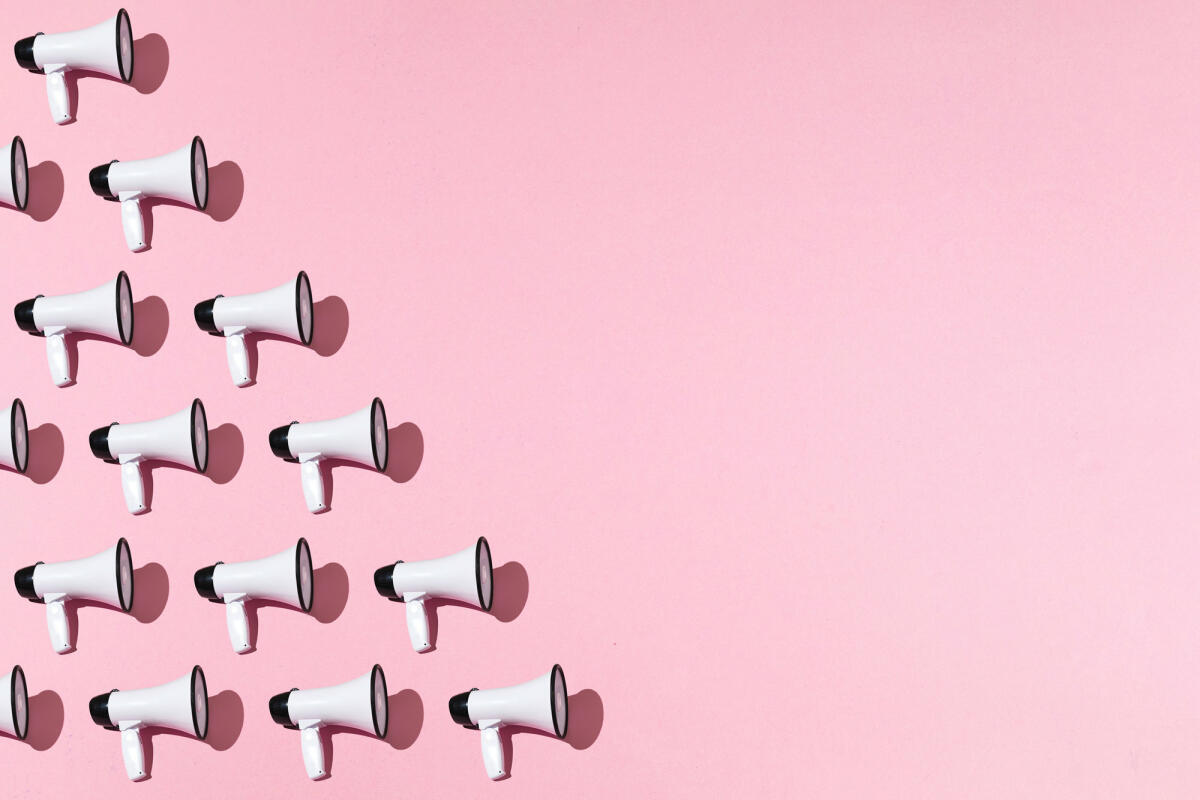 Weißes Megaphon-Muster mit schwarzem Ornament auf rosa Hintergrund auf der linken Seite, mit Kopierraum © DBenitostock / Getty Images