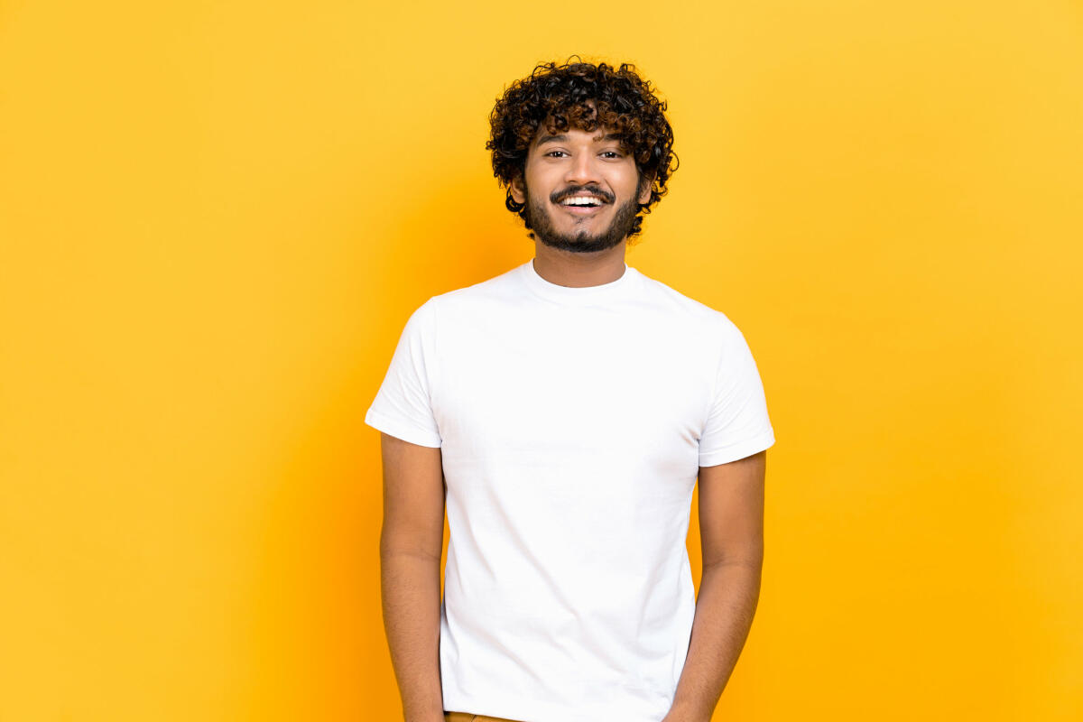 Porträt eines gutaussehenden, attraktiven, positiv lockigen indischen oder arabischen Mannes, der ein weißes Basic-T-Shirt trägt. © Kateryna Onyshchuk / Getty Images