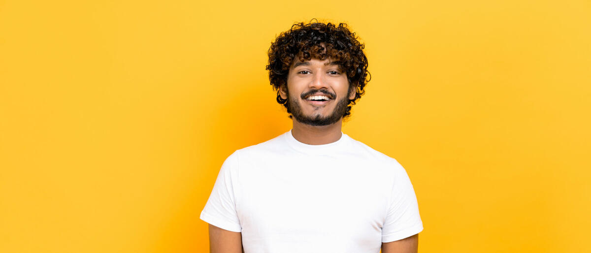 Porträt eines gutaussehenden, attraktiven, positiv lockigen indischen oder arabischen Mannes, der ein weißes Basic-T-Shirt trägt. © Kateryna Onyshchuk / Getty Images