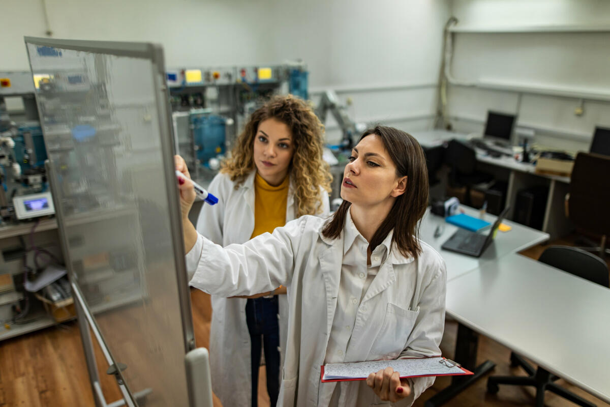 Ingenieure am arbeiten und eine schreibt auf Whiteboard im mechanischen Labor  © chabybucko/ Getty Images