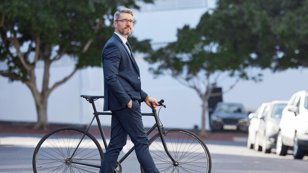 Aufnahme eines reifen Geschäftsmannes, der mit einem Fahrrad in der Stadt pendelt © PeopleImages / Getty Images