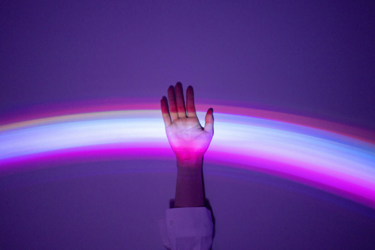 Hand, die sich meldet und in einem lila Lichtspiel aufleuchtet © Qi Yang / Getty Images